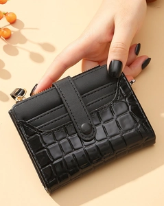 Close-up of black crocodile pattern wallet with gold zipper and snap button closure