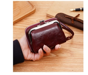 Primo piano del portafoglio vintage bordeaux con chiusura a scatto e cinturino su legno