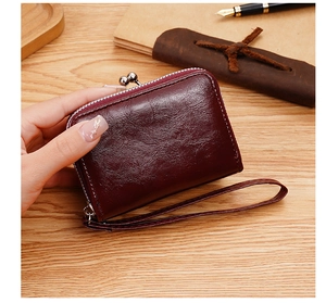 Dettaglio del portafoglio vintage in pelle cerata bordeaux con chiusura a sfera e zip