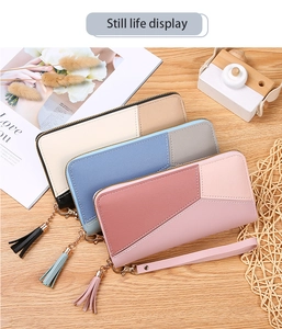 Detailed view of color-block long wallets with tassel pendants and wrist straps on wood