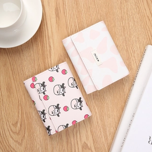 Three-fold mini wallet with cow print and strawberry pattern on warm wooden background