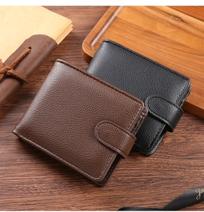 Detail of bifold wallets in dark brown and black lychee grain PU leather on wood surface