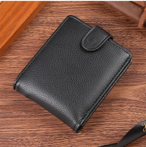 Close-up of black litchi grain leather wallet with metal snap closure on wood surface