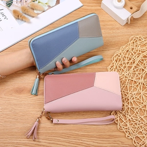 Minimalist long zip wallets with geometric patchwork and tassels on a wooden surface
