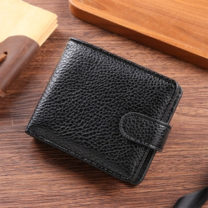 Close-up of black leather wallet with lychee grain texture and snap fastener on wood