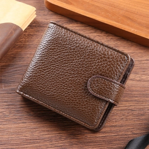 Close-up of brown litchi pattern leather wallet with snap closure on a wooden desk