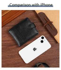 Size comparison of the compact black leather wallet next to an iPhone on a wooden desk