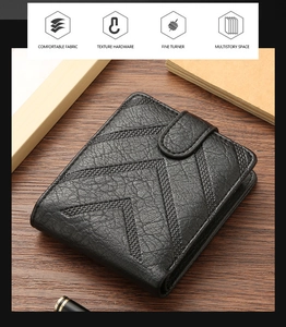 Detail of black litchi grain leather wallet with V-shaped embossing on wooden desk