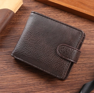 Close-up of brown leather wallet with lychee grain texture on a wooden desk