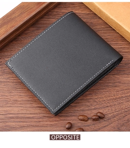 Close-up of black lychee grain leather men's wallet with white stitching on wood surface