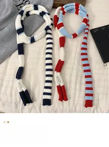 Détail d'écharpes en tricot à rayures rouges et bleues avec étiquette KN STUDIO