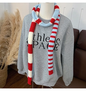 Détail de l'écharpe en maille rayée rouge et bleue avec motif texturé sur modèle