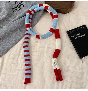 Détail d'une écharpe en maille à rayures rouges et bleues avec étiquette tissée blanche