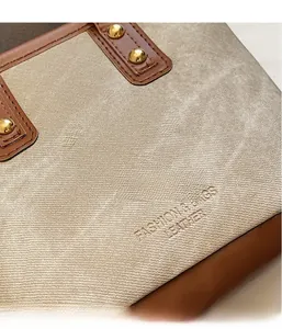 Nahaufnahme der Canvas-Textur und braunem Lederbesatz mit goldenen Nieten an der Beuteltasche