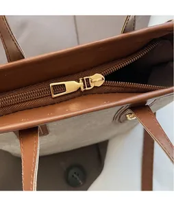 Nahaufnahme des goldenen Reißverschlusses und Lederbesatzes an der Canvas-Handtasche