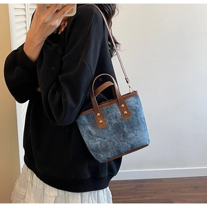 Detail der Vintage-Blau-Canvas-Tasche mit braunem Lederbesatz und goldenen Nieten