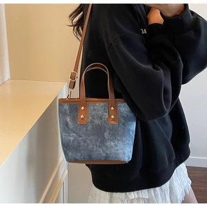Detail of vintage patchwork denim tote bag with brown leather straps and metal rivets