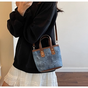 Details der Retro-Eimertasche aus blauem Denim und braunem Leder mit Goldnieten