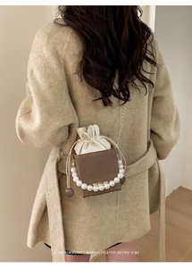 Close-up of pearl handle and chain strap on a textured brown bucket bag for women
