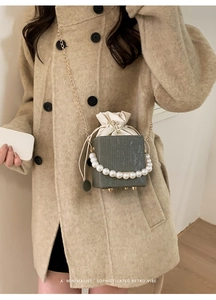 Close-up of retro box bag in deep grey-green featuring pearl handle and gold chain strap