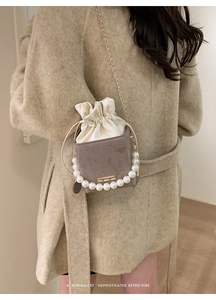 Detail of retro mini bucket bag featuring pearl handle and metallic chain strap