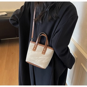 Lifestyle view of woman wearing a beige canvas bucket bag with brown leather accents