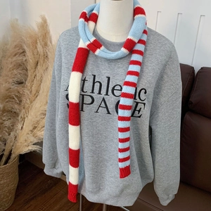 Écharpe en tricot rayé rouge, blanc et bleu portée sur un sweat à capuche gris
