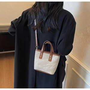 Detail of grey stone-patterned crossbody bag with brown leather handles and brand text