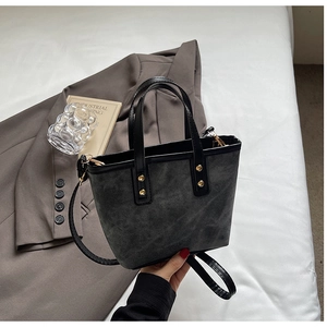 Detail of dark grey bucket bag with matte finish featuring golden metallic rivets and hooks
