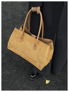 Detail of a large ginger yellow suede tote bag featuring premium matte texture and stitching