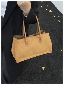 Détail macro du sac cabas en daim camel avec de longues lanières sur le sac à bandoulière