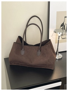 Macro view of dark brown suede tote bag showing matte texture and slim shoulder straps