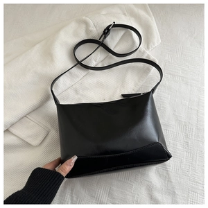 Detail of minimalist black PU leather tote bag with silver buckle and adjustable strap