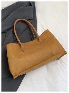 Top view of brown corduroy tote bag with leather straps on a dark grey wool coat