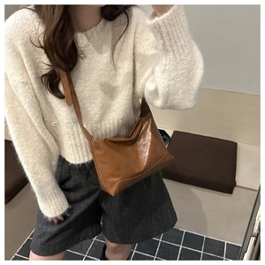 Dettaglio di una borsa tote in pelle cerata marrone con texture naturale e tracolla lunga