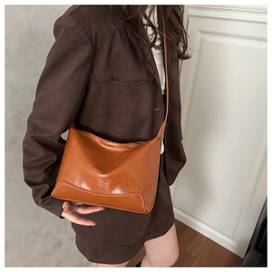 Brown faux leather crossbody bag with decorative stitching shown with model outfit