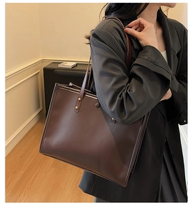 Macro view of textured dark brown leather tote with golden rivet detail and strap