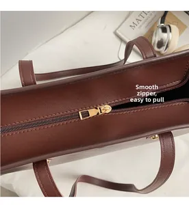 Close-up of smooth gold metal zipper and stitching on deep brown faux leather tote bag