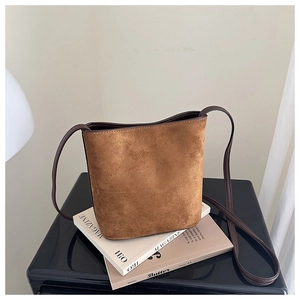 Detail of warm brown suede texture on a minimalist bucket bag with long shoulder strap