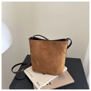 Detailed view of the dark brown suede bucket bag with leather strap on a studio display