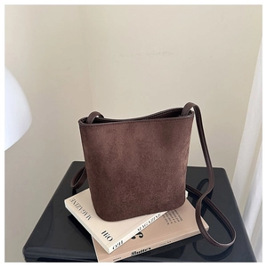 Detailed close-up of retro brown frosted suede bucket bag texture on fashion magazines