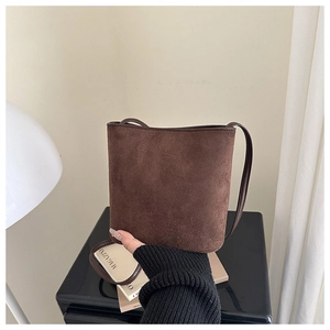 Detail of dark brown suede bucket bag texture and slim leather shoulder strap