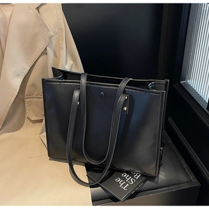 Close-up of matte black tote bag showing metal rivets and sleek magnetic button closure
