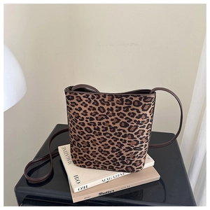 Detail of leopard print bucket bag with leather strap on minimalist magazine background