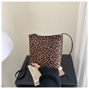 Detailed close-up of leopard print crossbody bag with sleek brown strap on a magazine