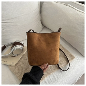 Detail of a brown suede bucket bag featuring a minimalist matte finish on a sofa