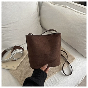 Detailed view of the dark brown suede bucket bag featuring a minimalist matte texture