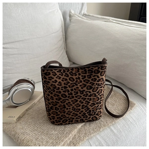 Detail of leopard print bucket bag with leather strap on a soft minimalist background