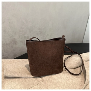 Detail of a dark brown suede bucket bag featuring high-quality matte leather texture