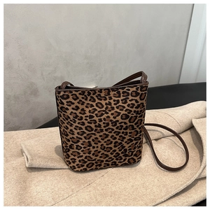 Detail of leopard print bucket bag with brown trim on ivory coat background